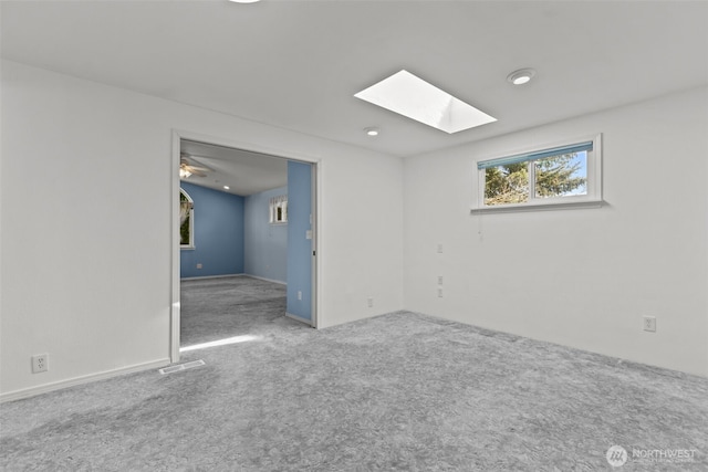 unfurnished room featuring a skylight, visible vents, and carpet