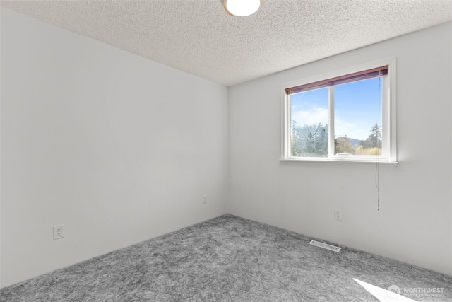 carpeted spare room with a textured ceiling and visible vents