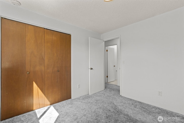 unfurnished bedroom with carpet floors, a closet, and a textured ceiling