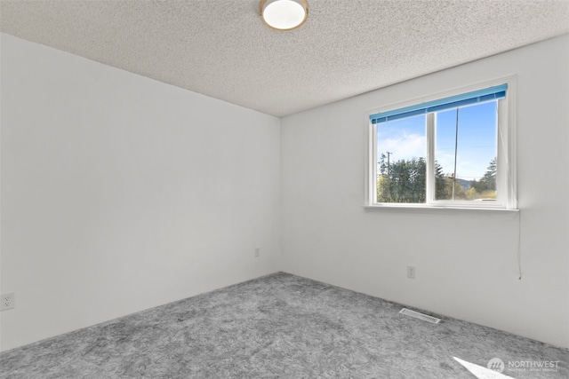 unfurnished room featuring carpet floors, a textured ceiling, and visible vents