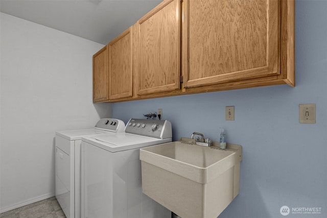 clothes washing area featuring a sink, cabinet space, and washing machine and clothes dryer