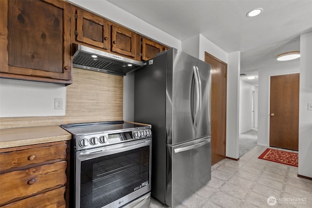 kitchen featuring exhaust hood, appliances with stainless steel finishes, light countertops, light floors, and backsplash