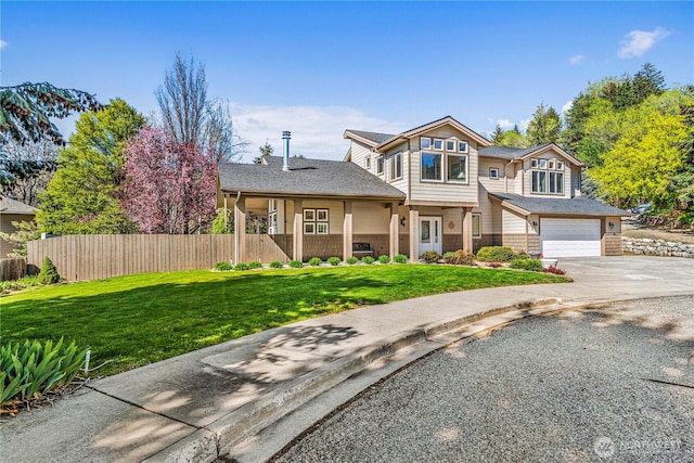 traditional home with an attached garage, driveway, a front yard, and fence