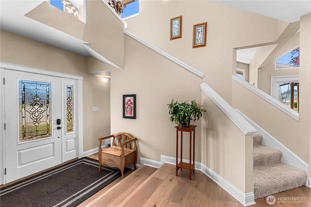 foyer entrance featuring stairway, a high ceiling, wood finished floors, and baseboards