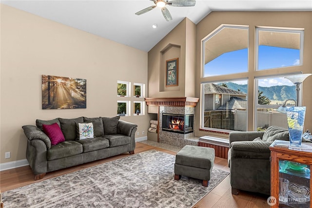 living area featuring a tile fireplace, a ceiling fan, wood finished floors, and plenty of natural light