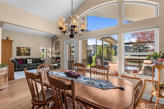 dining room featuring light wood-type flooring, high vaulted ceiling, and a chandelier