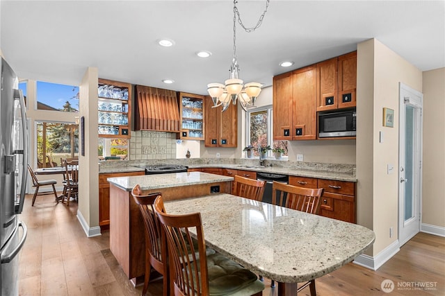 kitchen featuring brown cabinets, recessed lighting, a center island, black appliances, and custom range hood