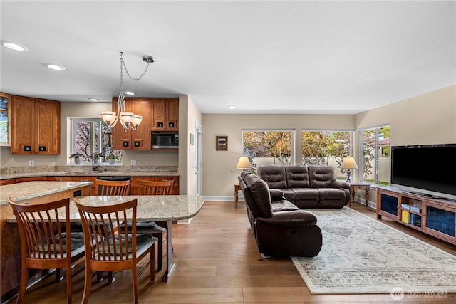 living room featuring baseboards, light wood-style floors, a chandelier, and recessed lighting