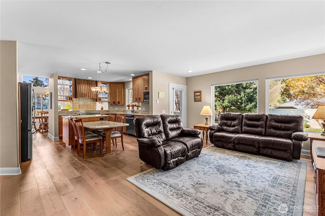 living area featuring light wood-type flooring, an inviting chandelier, baseboards, and recessed lighting