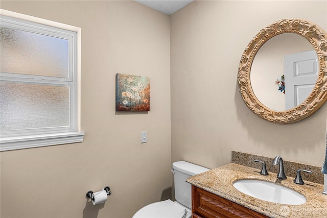 half bathroom featuring a wealth of natural light, toilet, and vanity