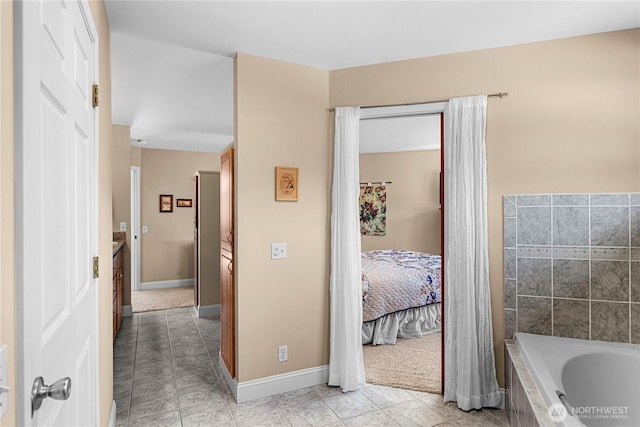 bathroom featuring baseboards, ensuite bath, tile patterned floors, and tiled tub