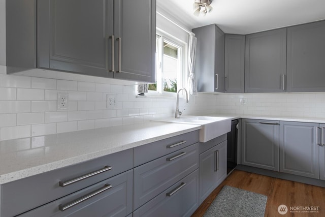 kitchen with light stone countertops, gray cabinetry, tasteful backsplash, and dark wood-type flooring