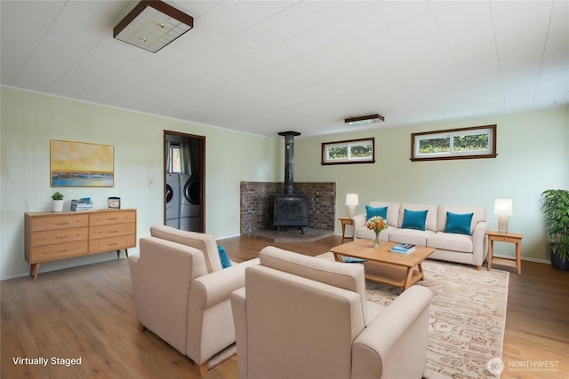 living room with washer and dryer, a wood stove, and light wood-type flooring