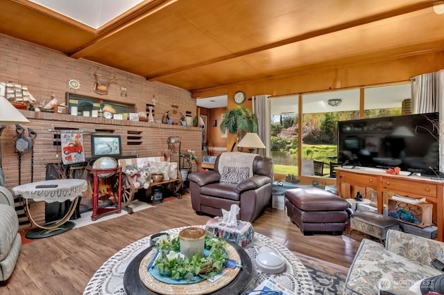 living room with brick wall, beam ceiling, and wood finished floors