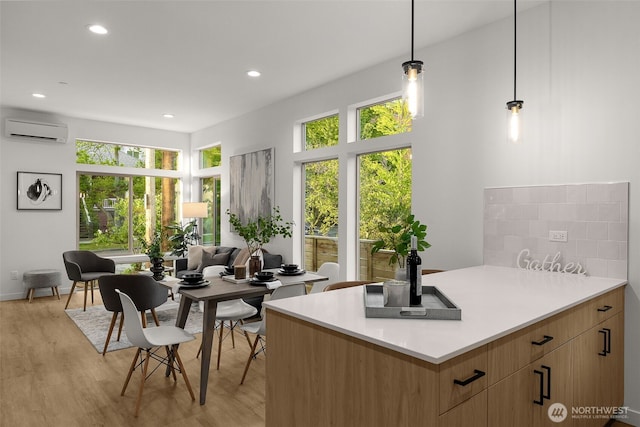 kitchen featuring a wall mounted air conditioner, light wood-style flooring, plenty of natural light, light countertops, and recessed lighting
