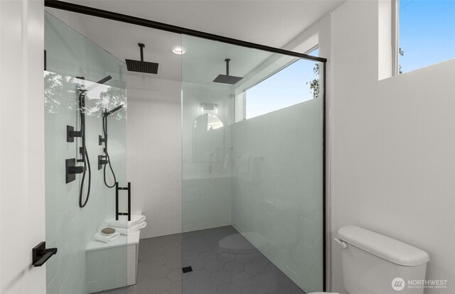 full bathroom featuring toilet, plenty of natural light, walk in shower, and tile patterned flooring