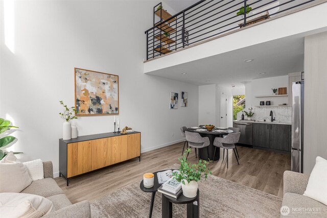 living area featuring light wood-type flooring, baseboards, and a towering ceiling