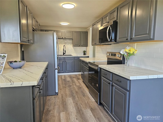 16738 2nd Ave NE, Shoreline, WA 98155 - kitchen with stainless steel appliances, a sink, tasteful backsplash, light wood-type flooring, and gray cabinets
