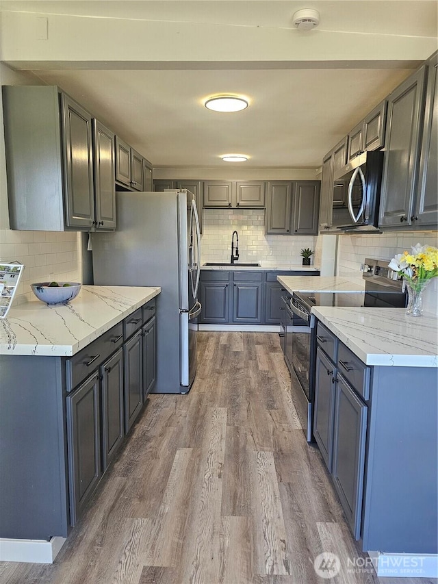 16738 2nd Ave NE, Shoreline, WA 98155 - kitchen featuring appliances with stainless steel finishes, a sink, tasteful backsplash, wood finished floors, and light stone counters