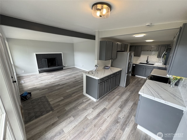16738 2nd Ave NE, Shoreline, WA 98155 - kitchen with stainless steel appliances, gray cabinets, light wood-style floors, tasteful backsplash, and light stone counters