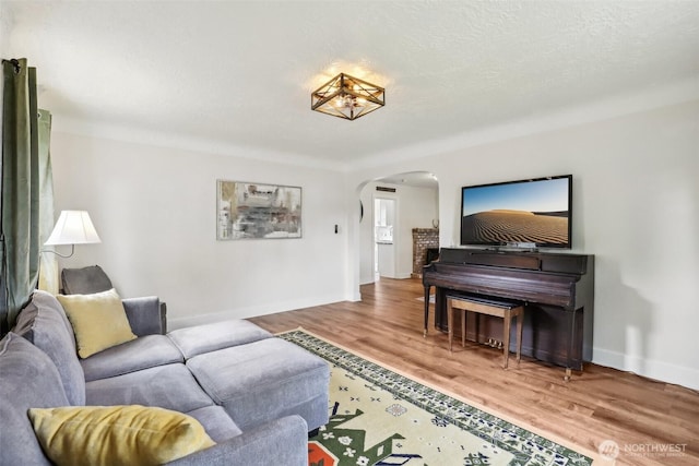 living room featuring arched walkways, baseboards, and wood finished floors