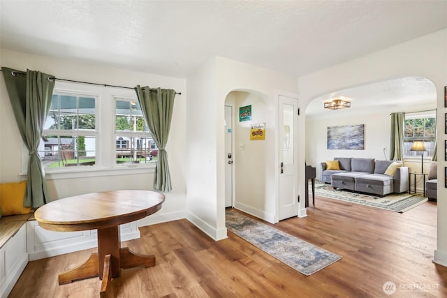 dining space with baseboards, arched walkways, and wood finished floors