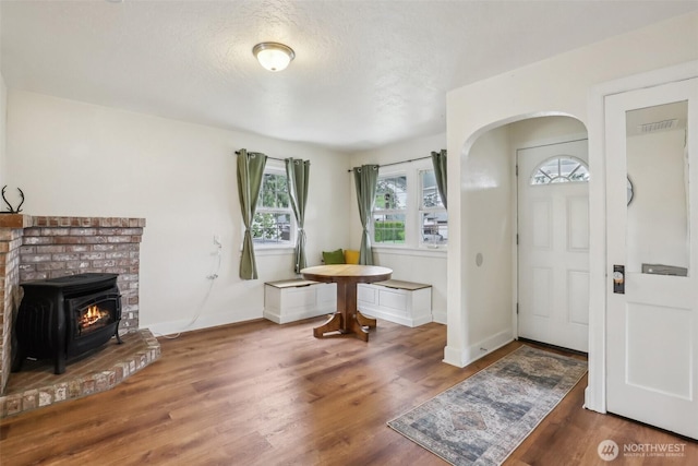 entrance foyer with visible vents, wood finished floors, baseboards, a textured ceiling, and arched walkways
