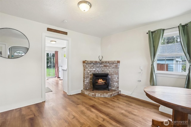 living room with a healthy amount of sunlight, baseboards, a brick fireplace, and wood finished floors