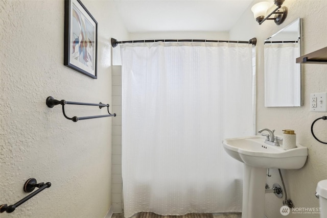 bathroom featuring a textured wall and toilet