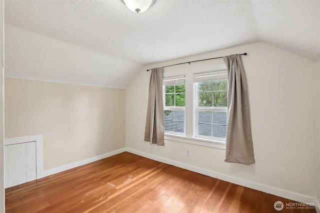 bonus room featuring baseboards, vaulted ceiling, and hardwood / wood-style flooring
