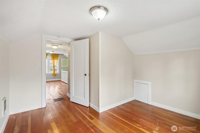 bonus room with baseboards, vaulted ceiling, hardwood / wood-style floors, and visible vents