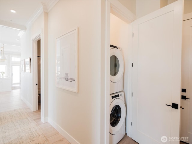 204 Market St Unit A, Pacific Beach, WA 98571 - laundry room featuring laundry area, crown molding, light wood-style floors, baseboards, and stacked washing maching and dryer