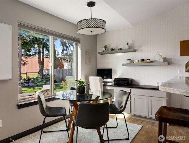 dining space featuring light wood finished floors and wallpapered walls
