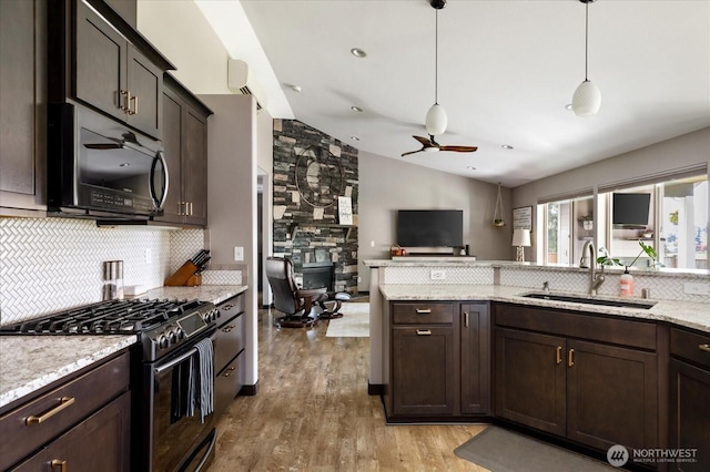 kitchen featuring vaulted ceiling, a sink, ceiling fan, backsplash, and gas stove