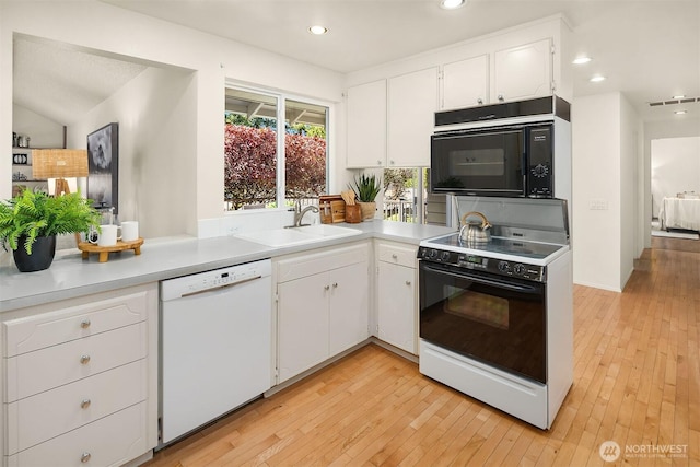 kitchen featuring white dishwasher, electric range, black microwave, a sink, and visible vents