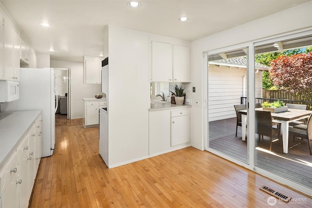 kitchen featuring white appliances, light countertops, a sink, and light wood-type flooring