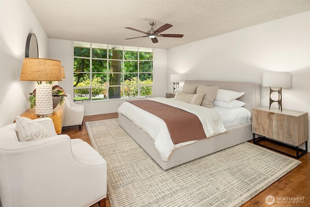 bedroom with a ceiling fan, a textured ceiling, and wood finished floors
