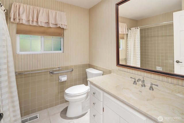 bathroom with visible vents, tile patterned flooring, toilet, wallpapered walls, and a wainscoted wall