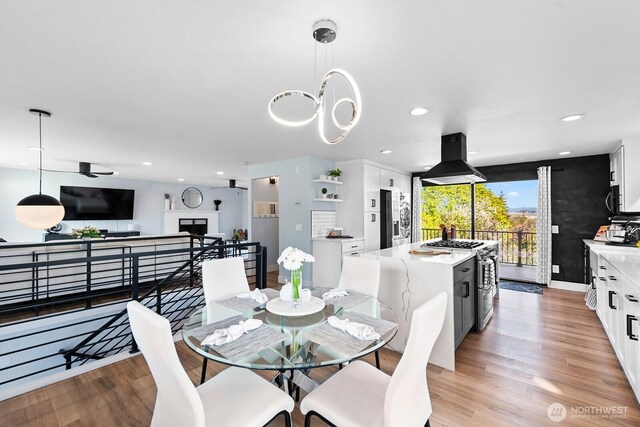 dining room with a fireplace, light wood-style floors, and recessed lighting