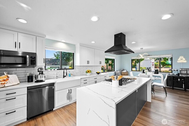 kitchen with plenty of natural light, island range hood, stainless steel appliances, and a sink