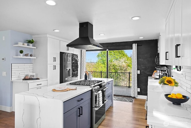 kitchen with open shelves, island exhaust hood, stainless steel appliances, baseboards, and light stone countertops