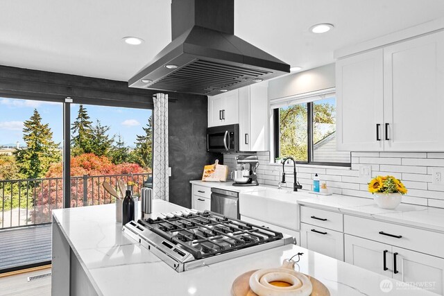 kitchen with visible vents, stainless steel appliances, island exhaust hood, and light stone counters
