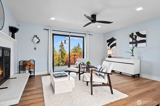living area with recessed lighting, light wood finished floors, baseboards, a fireplace, and ceiling fan