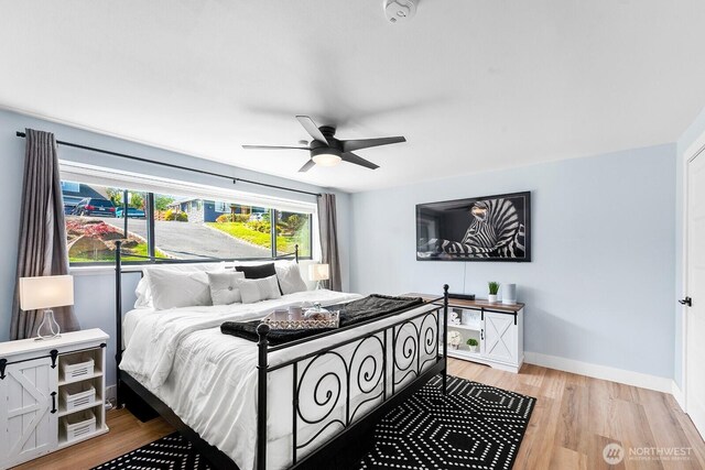 bedroom with light wood-type flooring, a ceiling fan, and baseboards