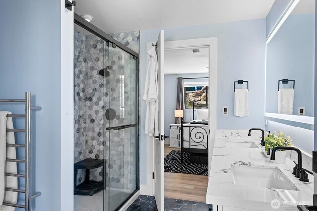 ensuite bathroom featuring a shower stall, ensuite bath, a sink, and double vanity