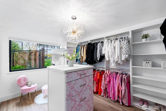 spacious closet with wood finished floors and a chandelier