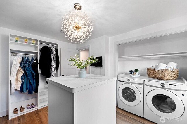 laundry room featuring separate washer and dryer, laundry area, wood finished floors, and a notable chandelier