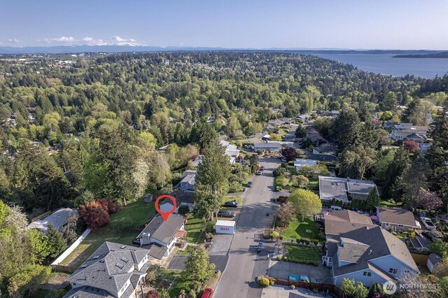drone / aerial view featuring a forest view, a water view, and a residential view