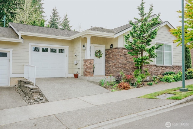 view of front of house featuring concrete driveway, an attached garage, a shingled roof, and stone siding