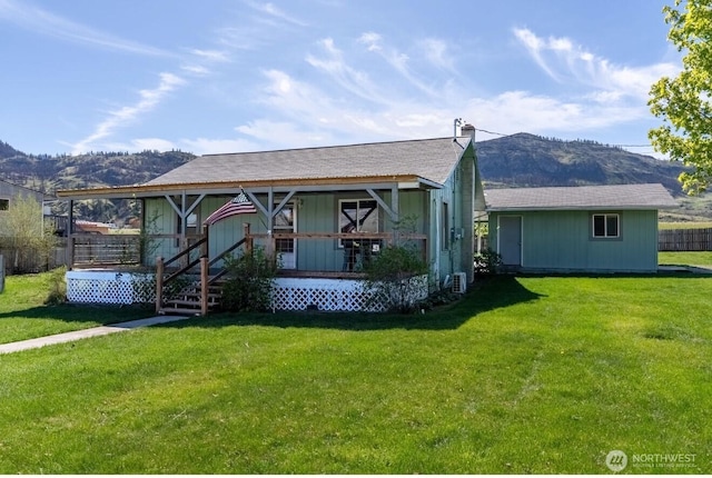 ranch-style house with a shingled roof, a front yard, covered porch, and a mountain view